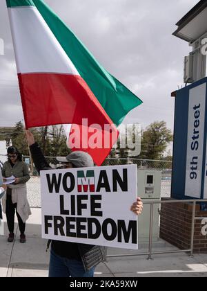 Reno, Nevada, Stati Uniti. 22nd Ott 2022. Un manifestante porta con sé una bandiera iraniana e un cartello che dice: ''Donna, vita, libertà'' durante una marcia dimostrativa che condanna il governo iraniano e la morte di Masha Amini. A partire dall'Università del Nevada, centinaia di più di 2.000 iraniani americani di Reno hanno marciato attraverso il centro di Reno chiedendo la fine di ciò che hanno detto era il regime religioso oppressivo di IranÃ.Masha Amini è stata una figura centrale nelle manifestazioni. Amini è stato rapito dalla polizia morale iraniana e presumibilmente è stato assassinato mentre era in custodia del governo iraniano. (CRE Foto Stock