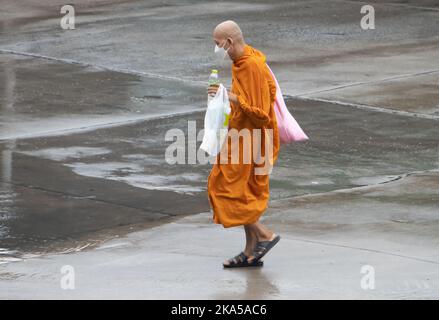 SAMUT PRAKAN, THAILANDIA, ottobre 11 2022, Un monaco buddista cammina su una strada bagnata Foto Stock