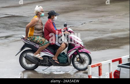 SAMUT PRAKAN, THAILANDIA, ottobre 11 2022, due donne cavalca in moto sulla strada bagnata. Foto Stock