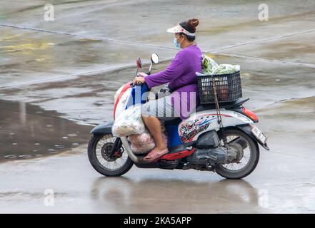 SAMUT PRAKAN, THAILANDIA, 26 2022 SETTEMBRE, Una donna con grande carico cavalca una moto sotto la pioggia Foto Stock
