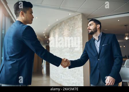 I concorrenti non hanno alcuna chance di opporsi a questa partnership: Due giovani uomini d'affari si stringono le mani in un ufficio moderno. Foto Stock