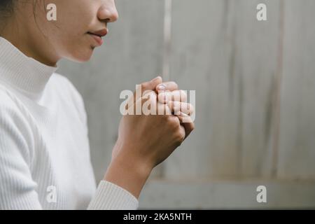 Donna che prega per ringraziare dio che prega insieme con le sue mani per pensare ad un Dio amorevole, noi lodiamo Dio con luce luce flare nella natura verde. Foto Stock