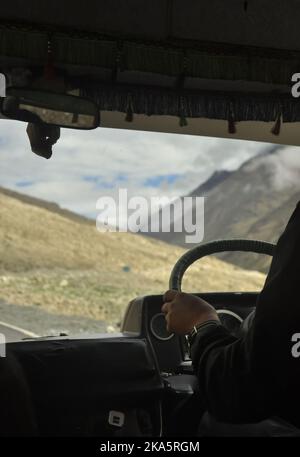 Persona non riconosciuta che guida un pulmino passeggero (tempo Traveller) in autostrada Manali-Leh con splendida vista sulle montagne durante la stagione estiva. Foto Stock