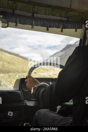 Persona non riconosciuta che guida un pulmino passeggero (tempo Traveller) in autostrada Manali-Leh con splendida vista sulle montagne durante la stagione estiva. Foto Stock