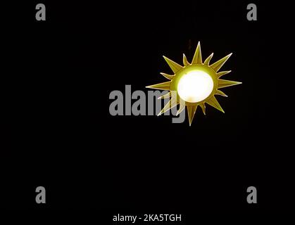 Lampada a forma di sole su sfondo nero Foto Stock