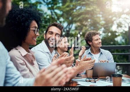 Celebrare un altro grande successo: Un gruppo di colleghi applaudente durante una riunione in un bar. Foto Stock