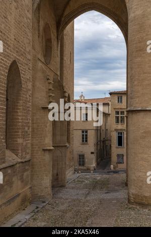 Vista panoramica della vecchia strada di ciottoli e degli antichi edifici incorniciati dal portale d'ingresso della cattedrale di San Pietro nel centro storico di Montpellier, Francia Foto Stock