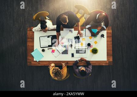 Saltando a destra nel lavoro che deve essere fatto. Immagine ad angolo alto di un gruppo di uomini d'affari che hanno una riunione in un ufficio moderno. Foto Stock