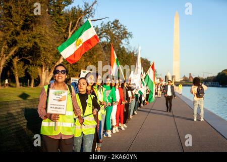 Washington, Stati Uniti. 29th Ott 2022. La gente forma una catena umana intorno alla piscina riflettente sul National Mall durante una marcia per Mahsa (Zhina) Amini, la giovane donna che è morta in custodia della polizia morale iraniana. L'evento è stato uno dei tanti a livello mondiale in cui si è formata una catena umana in solidarietà con i manifestanti iraniani. Le proteste che continuano fino alla settima settimana rappresentano la più grande minaccia per il regime islamico degli ultimi decenni. (Foto di Allison Bailey/SOPA Images/Sipa USA) Credit: Sipa USA/Alamy Live News Foto Stock