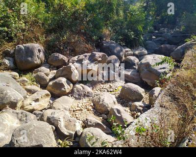 Letto di fiume asciutto riempito con grandi pietre di rotolamento con montagne sullo sfondo. Himalayan Regione Uttarakhand India. Foto Stock