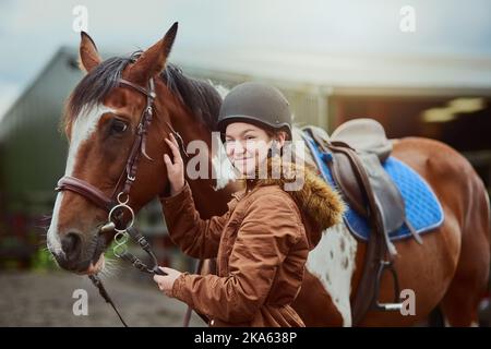 I migliori amici vengono in tutte le dimensioni. Una ragazza adolescente in piedi accanto al suo pony in una fattoria. Foto Stock