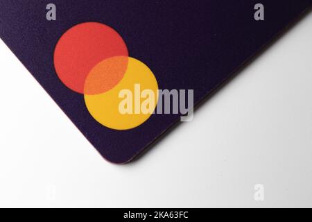 Il logo Mastercard su una carta di credito viola, visto mentre posizionato su una scrivania bianca. Foto Stock