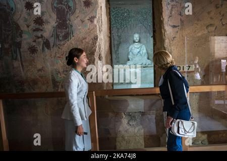 Dunhuang, Cina 20181013. La regina Sonja e il re Harald studiano una scultura nella grotta 16. Sabato, la coppia reale ha visitato le famose grotte di Mogao a Dunhuang, provincia di Gansu, Cina occidentale. In 492 delle 735 grotte si trova la più completa collezione di arte buddista del mondo, risalente all'anno 366 dopo Cristo. Ci sono oltre 45.000 metri quadrati di murales e 2000 sculture dipinte nelle grotte. Per 34 anni, le grotte di Mogoa sono state nella lista dei desideri della regina Sonja. Due delle grotte visitate sono il n° 16 e il n° 17. Contengono una grande quantità di testi da 600 a 1200. La fondazione del Th Foto Stock