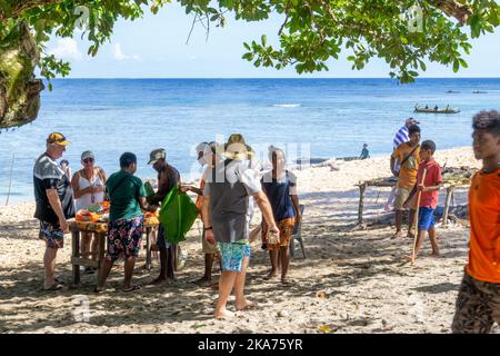 Gli abitanti del luogo preparano e cucinano pesce a fuoco aperto sulla spiaggia, sull'isola di Kiriwina, sulla provincia di Milne Bay, sulla Papua Nuova Guinea Foto Stock