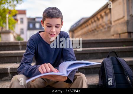 Ragazzo adolescente ingenwsed nella lettura di un libro Foto Stock