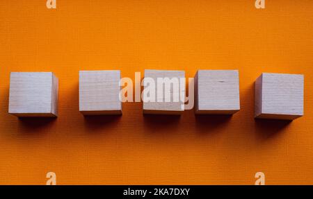 Cinque cubetti di legno su sfondo arancione, mocapo Foto Stock
