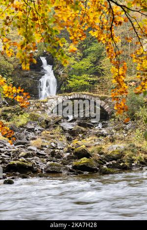 Ponte di Packhorse (conosciuto localmente come Ponte Romano) e cascata in autunno, Glen Lione, Scozia, Regno Unito Foto Stock