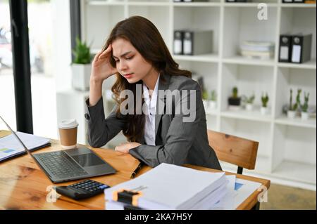 Stressato e premuroso giovane donna d'affari caucasica alla sua scrivania sentirsi sconvolto e insoddisfatto dei risultati del suo progetto di business, soffrendo f Foto Stock