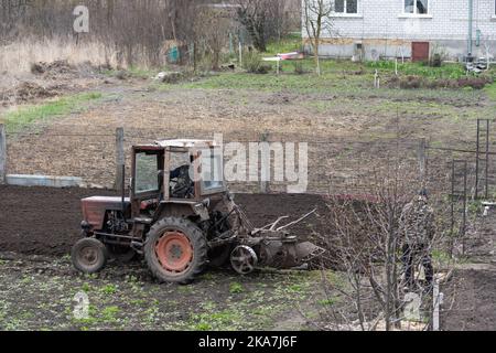 il trattore agricolo con aratro arpa il campo e si prepara alla semina. Foto Stock