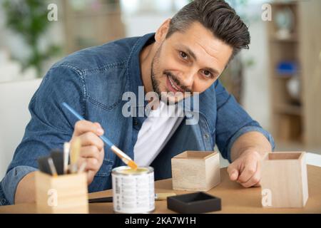 l'uomo tiene in mano una tazza per dipingere l'ornamento Foto Stock