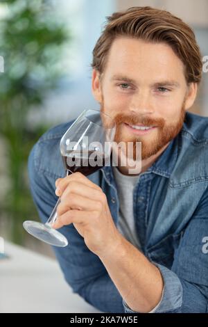 bel giovane uomo che odora vino rosso prima di beverlo Foto Stock