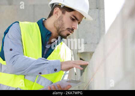 muratore da costruzione che installa mattone rosso con cazzuola Foto Stock