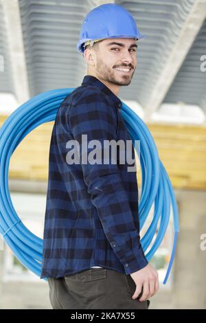 felice costruttore maschio che tiene tubi Foto Stock