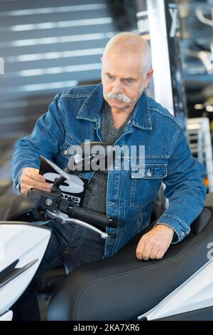 uomo anziano che controlla una motocicletta Foto Stock