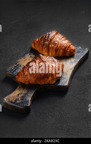 Croissant croccanti su un tavolo da servizio in legno scottato Foto Stock