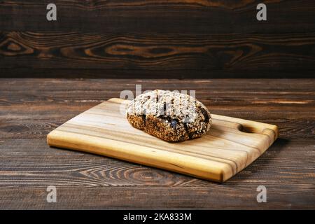 Pane artigianale di segale con albicocche secche, prugne e semi di girasole sul tagliere Foto Stock