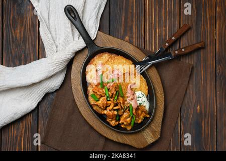 Vista dall'alto sui pancake di patate con chanterelle e maiale in padella di ghisa Foto Stock