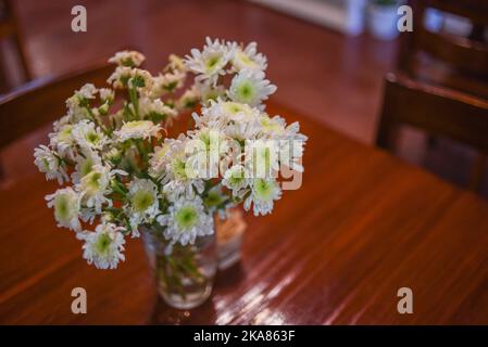 Un focus selettivo dei crisantemi bianchi in un vaso trasparente sul tavolo Foto Stock