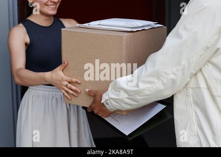Primo piano della consegna uomo che consegna scatola a donna sorridente in casa Foto Stock