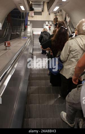 Passeggeri che scendono dalla scala mobile verso la stazione della metropolitana. Londra Inghilterra Foto Stock