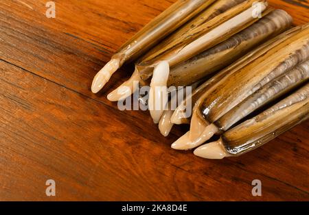 Guscio di rasoio allungato, rettangolare, pesce bivalve, solen marginatus su sfondo di legno Foto Stock