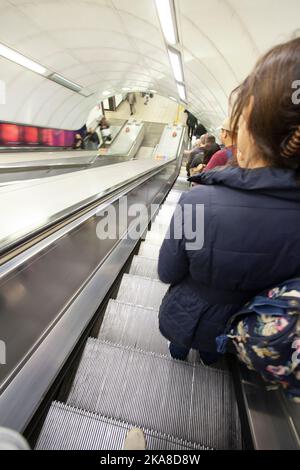 Persone che scendono le scale mobili fino alla stazione della metropolitana. Londra Inghilterra Foto Stock