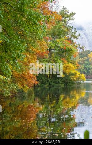 Il vivace colore autunnale si riflette in un lago fermo con il granito ricoperto di nebbia di Stone Mountain sullo sfondo dello Stone Mountain Park di Atlanta. Foto Stock