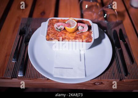 Pesce lasagne in una padella lucida sul tavolo Foto Stock