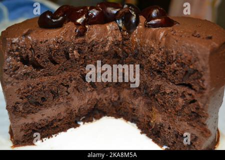 Torta al cioccolato sana ricoperta di ganache al cioccolato e ciliegie al liquore. Foto Stock