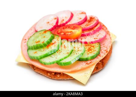 Panino Cracker croccante con cetriolo fresco, formaggio, salsiccia, rafano e pomodoro - isolato su bianco. Panini veloci e sani. Croccante con gustoso ripieno. Snack dietetico sano - isolamento Foto Stock