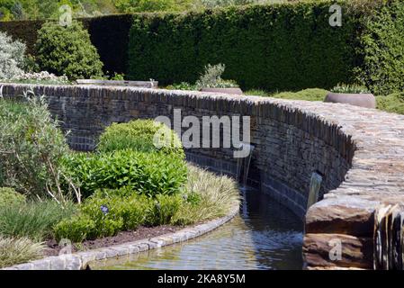 Cascata d'acqua attraverso il fresco Giardino a RHS Garden Rosemoor, Torrington, North Devon, Inghilterra, Regno Unito Foto Stock