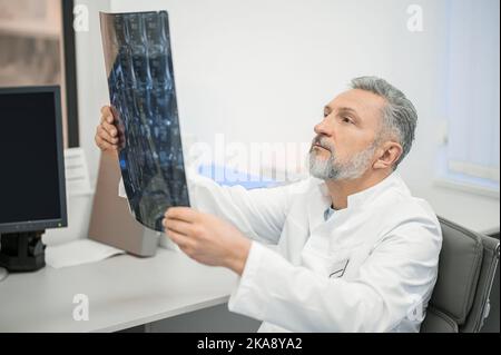 Medico di sesso maschile che esamina i risultati di MRI Foto Stock