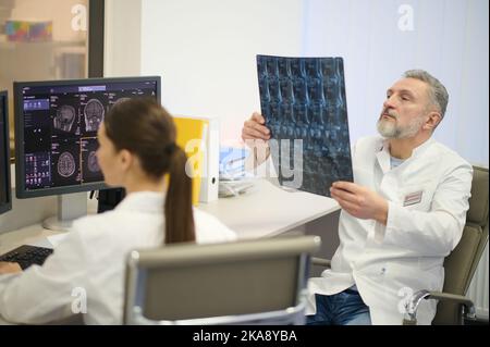 Medico di sesso maschile che esamina i risultati di MRI Foto Stock