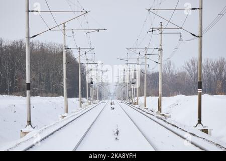 Ferrovia innevata durante la giornata invernale gelosa. Riduzione della prospettiva di due binari ferroviari vuoti. Foto Stock