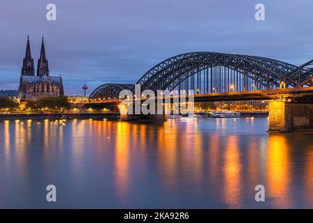 Una serata a Colonia con la Cattedrale e il Ponte Hohenzollern dopo il tramonto. Foto Stock