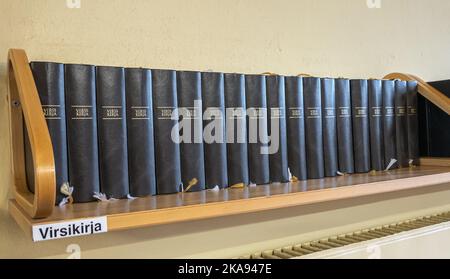 Finlandia, Kotka - 18 luglio 2022: Chiesa Parrocchiale di Kotka-Kymin o Seurakuntayhtymä. Primo piano, Shelf di libri di inno nero. Parete beige come sfondo. Foto Stock