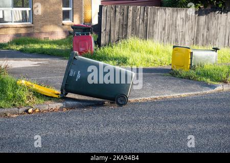 Vista dei cassonetti delle ruote dei rifiuti rovesciati dal forte vento che si posa a terra Foto Stock