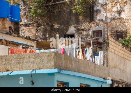 Stenditoio di vestiti asciuganti su un tetto di una casa. Una parete intemperita e di scappamento e serbatoi di accumulo dell'acqua fanno parte della scena. Foto Stock