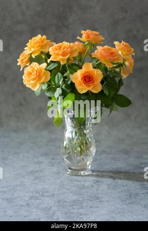Bouquet di rose crema in vaso di cristallo su fondo grigio Foto Stock
