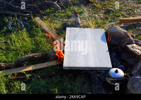 Marmo sul fuoco del campo per cucinare e teiera vicino al fuoco all'aperto in una giornata di sole estate Foto Stock